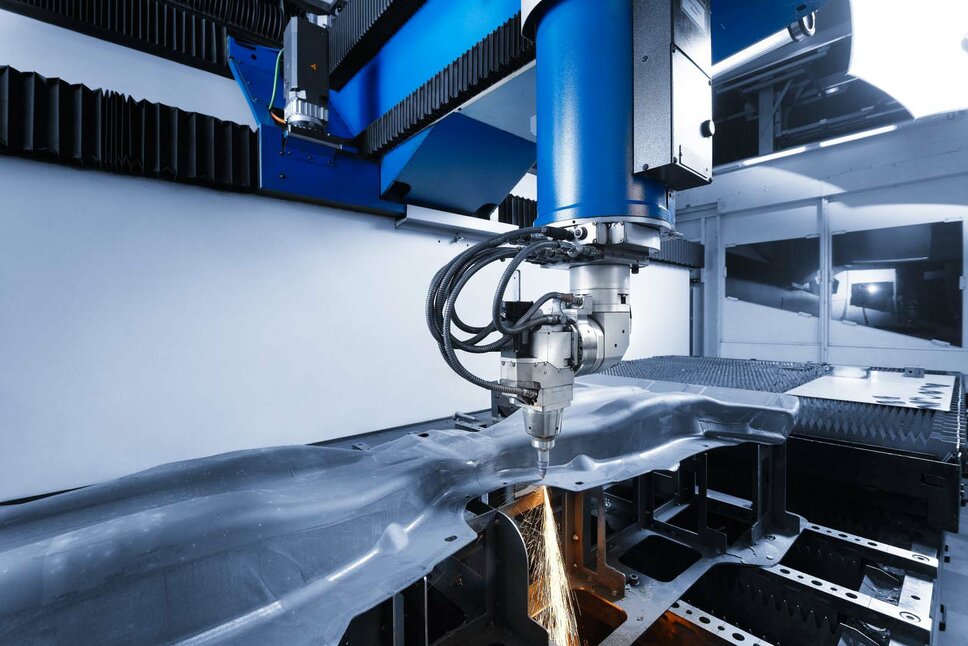 Präzise Laserschneidmaschine bei der Bearbeitung eines Bauteils. Die Maschine schneidet mit hoher Genauigkeit durch ein komplex geformtes Metallteil und erzeugt dabei Funken. Moderne Laserschneidtechnologie für die Fertigung von Automobilkomponenten.