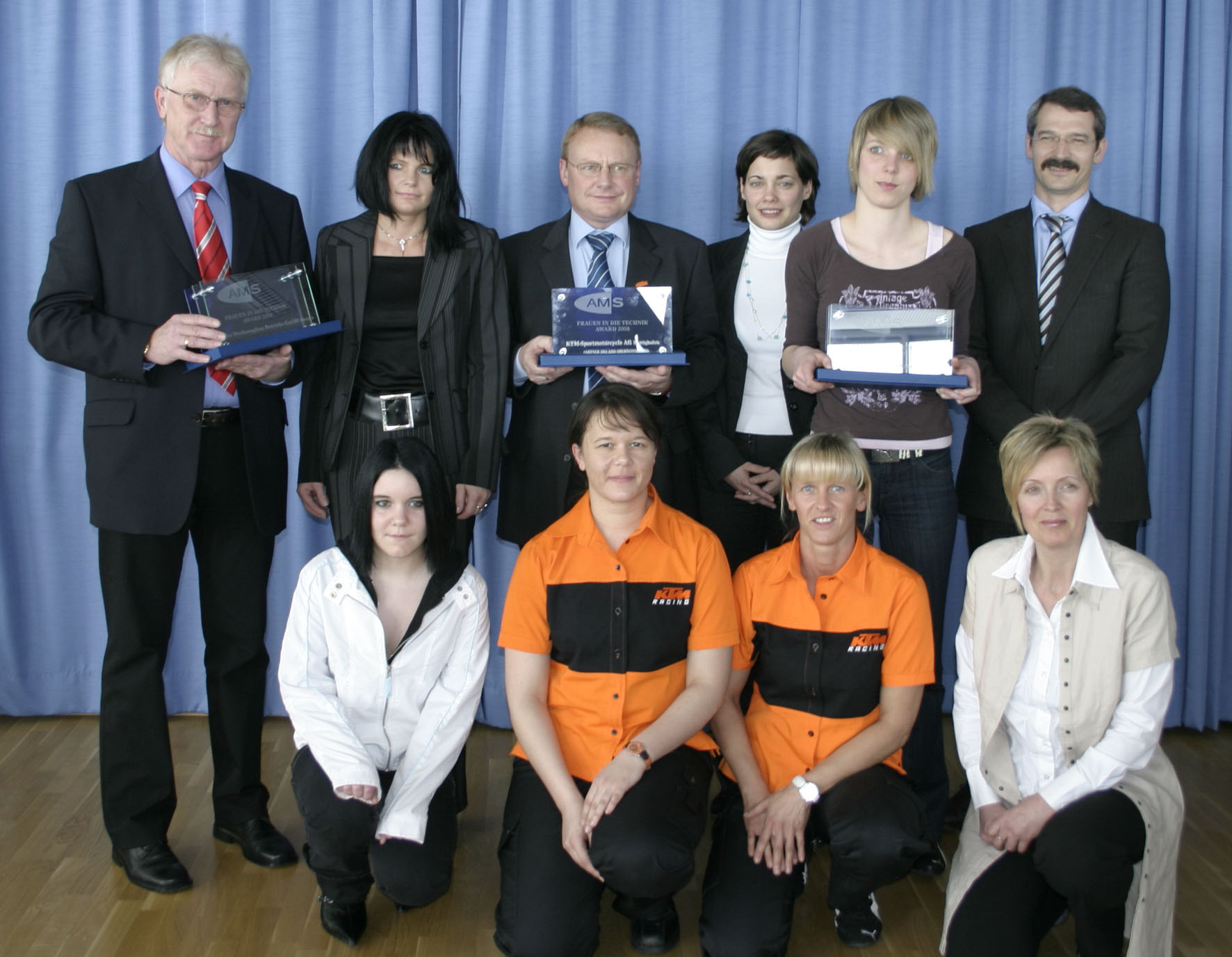 Gruppenfoto beim AMS Award Frauen in Technik, mit mehreren Teilnehmerinnen und Teilnehmern vor einer Bühne posierend.